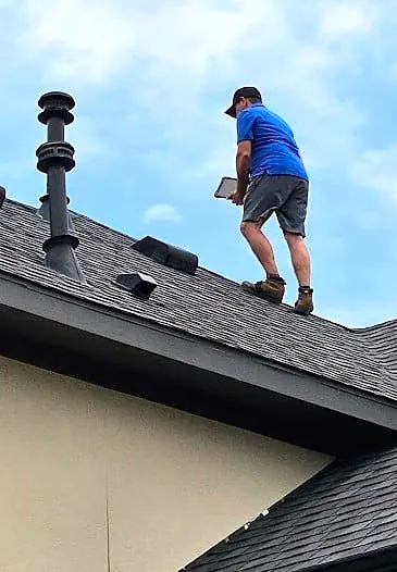 Roof inspector documenting damage with a tablet on a rooftop